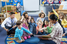 Group of preschool students sitting on carpet with teacher during story time