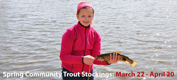 A girl proudly holding the trout she caught at a community trout lake.