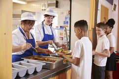 School cafeteria workers serving students lunch