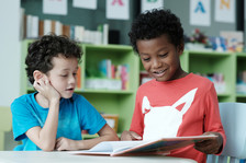 Two young, elementary school boys reading.