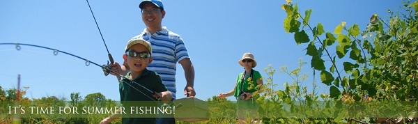 A father, mom and son walking to a lake's shore with their fishing rods.