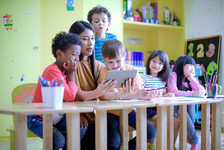 Preschool children with teacher, viewing tablet