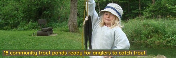 A young girl holding a trout she caught.