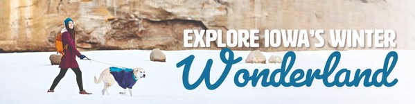 A lady and her dog walking in a Iowa state park in the winter.