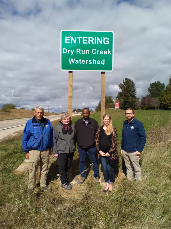 People stand beneath a sign for Dry Run Creek in Black Hawk County