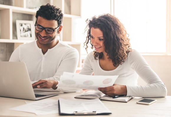 Man and woman reviewing paperwork and working on computer