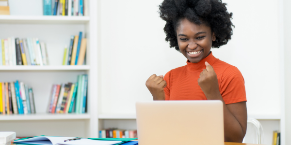 Woman at computer cheering because she won a grant for her library.
