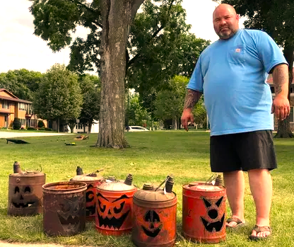 Brad Thill stands next to jack-o-lanterns made from gas tanks.