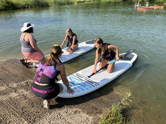 Teacher externs help day campers board paddleboards