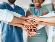Medical professionals putting their hands in a circle