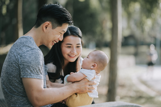 A man and woman holding their baby and smiling 