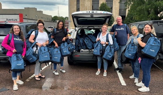Wellpoint members standing by a van holding backpacks