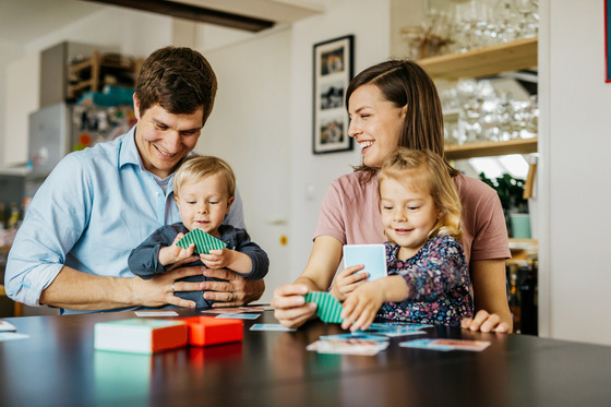 Dad and family playing with cards at kitchen table