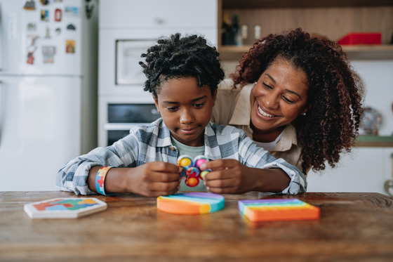 A mother playing with her autistic son at the kitchen table