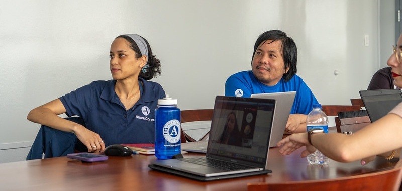 two individuals sitting at a table in front of a laptop