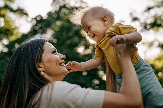 A mother holding her toddler up in the air 