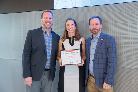Michelle Raymer holding an award with ASC representatives standing next to her