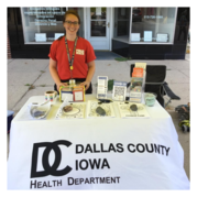 Abigail stands behind her table at a health fair. Various health promotion brochures are on the table