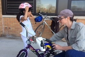 A child adjusts a bike helmet on her head