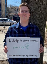 Zach Berg holding sign saying "I pledge to climate action by plant a tree"