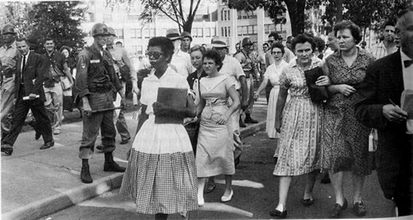 A member of the Little Rock Nine is shown walking  with angry white people behind her. 