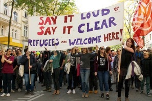 An image shows protestors marching for refugees rights. 