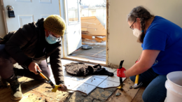 Students in the women's construction skills class remove tile from an entryway.