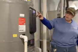 Christy is shown pointing to a heat pump water heater
