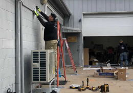 a worker installs a heat pump at the Bike Library