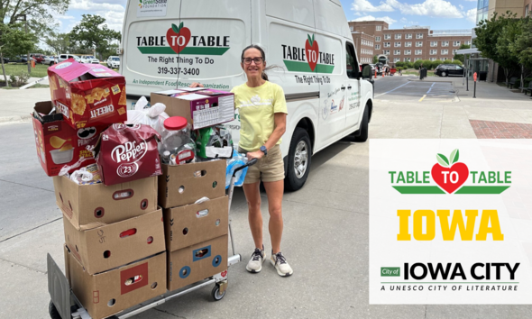 A stack of donated food is shown in front of the Table to Table van. 