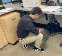 Image of Ed Teets installing equipment under a desk at a Idaho State Liquor store