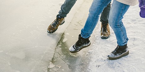 two people cautiously stepping onto icy ground