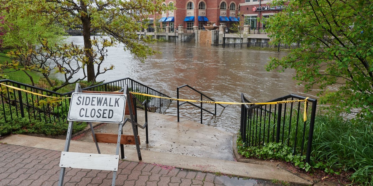 Sidewalk closed sign. Flooded river.