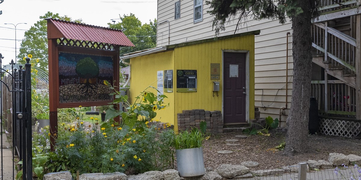 Mosaic sign and yellow shed in small community garden