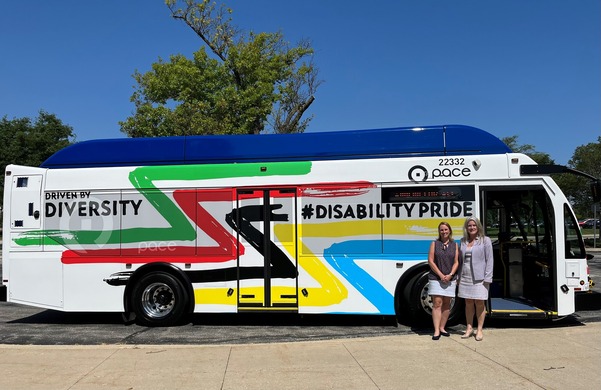 CMAP leaders standing and smiling in front of a Pace bus decorated for disability pride month