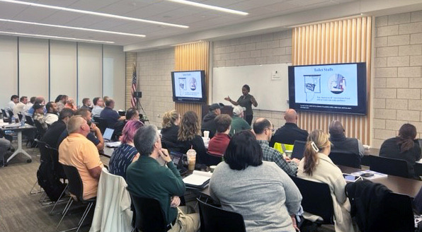 Felica Burton,  Accessibility Specialist, standing at a podium and presenting to an audience.