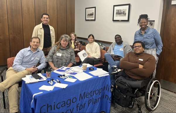CMAP staff gathered around a table at an accessibility training session. The group is facing the camera and smiling.