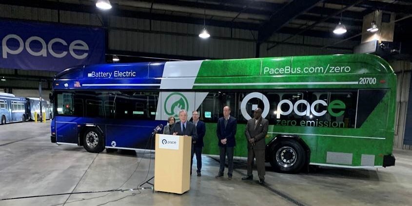 Senator Durbin speaks at podium in front of Pace electric bus