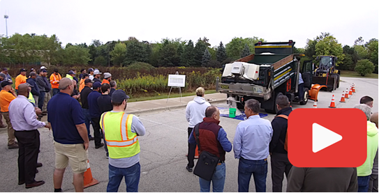 YouTube logo. Photo of people in parking lot gathered around salt truck