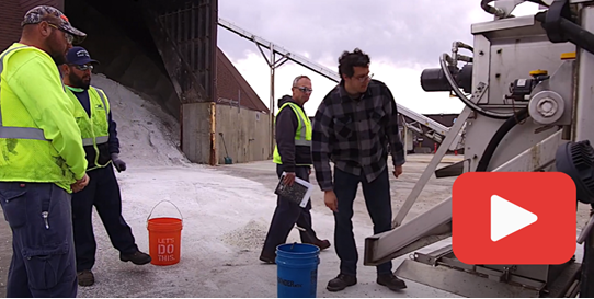 YouTube logo. Photo of person looking at machine next to salt shed