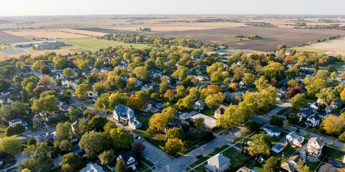 Aerial photo of residential area with trees. Farmland in background.