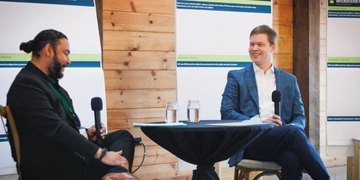 Enrique and Jonathan Burch speak together in front of audience