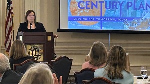 Erin speaking at podium next to screen with intro slide