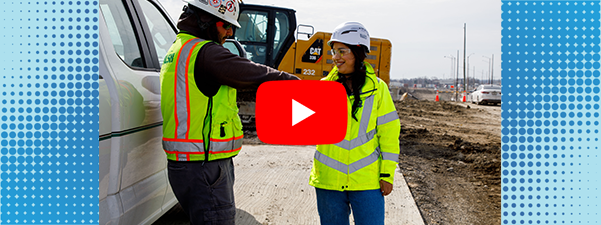 Two construction workers on roadway construction site shaking hands
