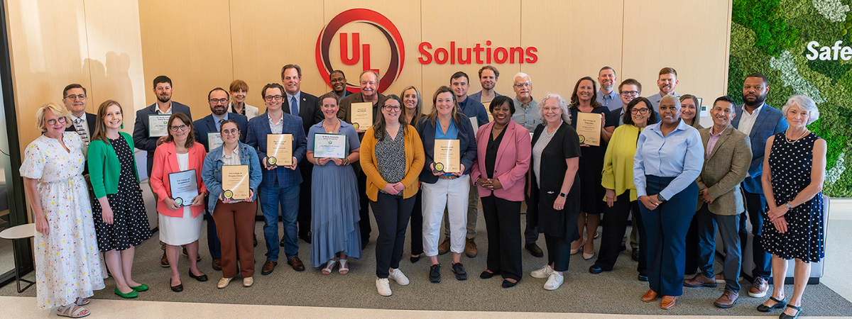 Group of people holding plaques and certificates in front of UL Solutions sign