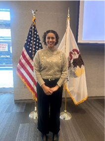 CCVA Interim Director Vanessa Walters stands in front of two flags at the Women's History Month event.