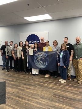 Cool DuPage, SCARCE, and BioMérieux staff hold up the earth flag presented by SCARCE