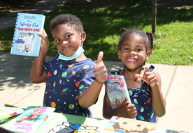Two children smiling and holding up books