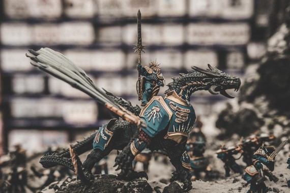 Tabletop figurine of a warrior with a sword riding an armored dragon.