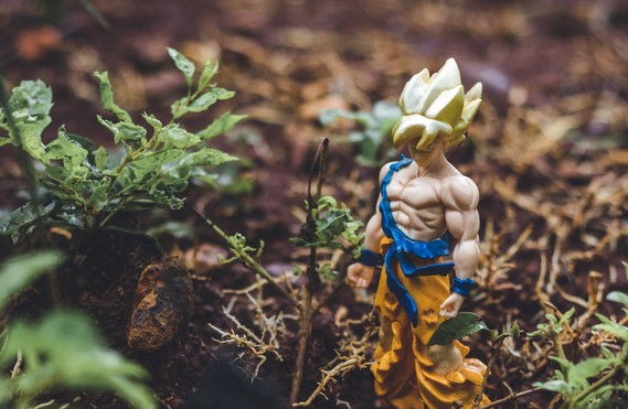 A Goku figurine standing in grass and soil.